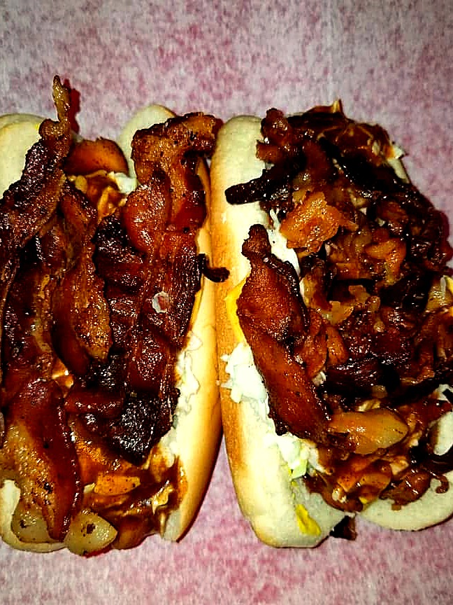 Two Tony's hot dogs piled high with bacon and grilled onions